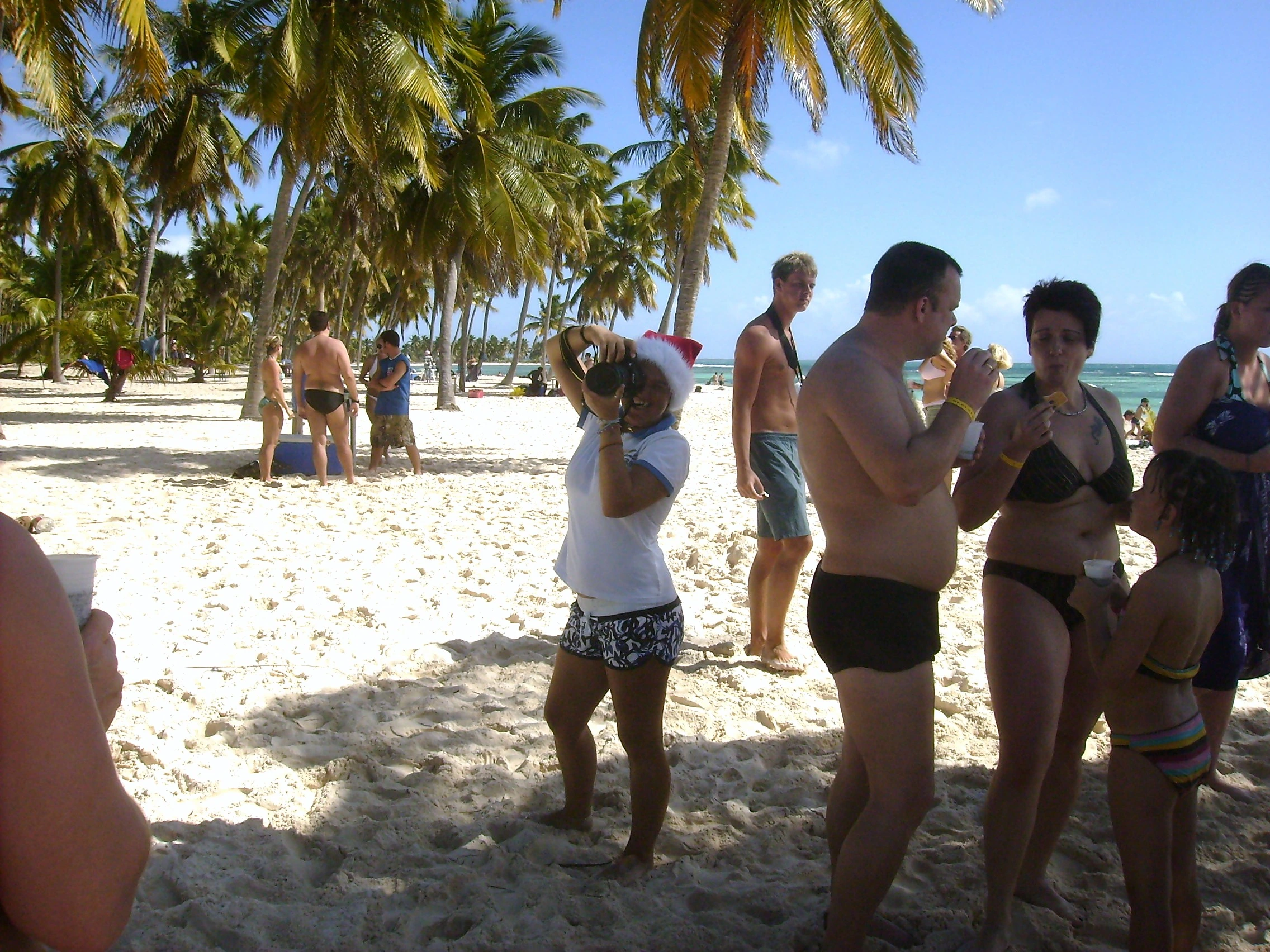 Visitors stand beneath coconut palms on Saona’s white beach.