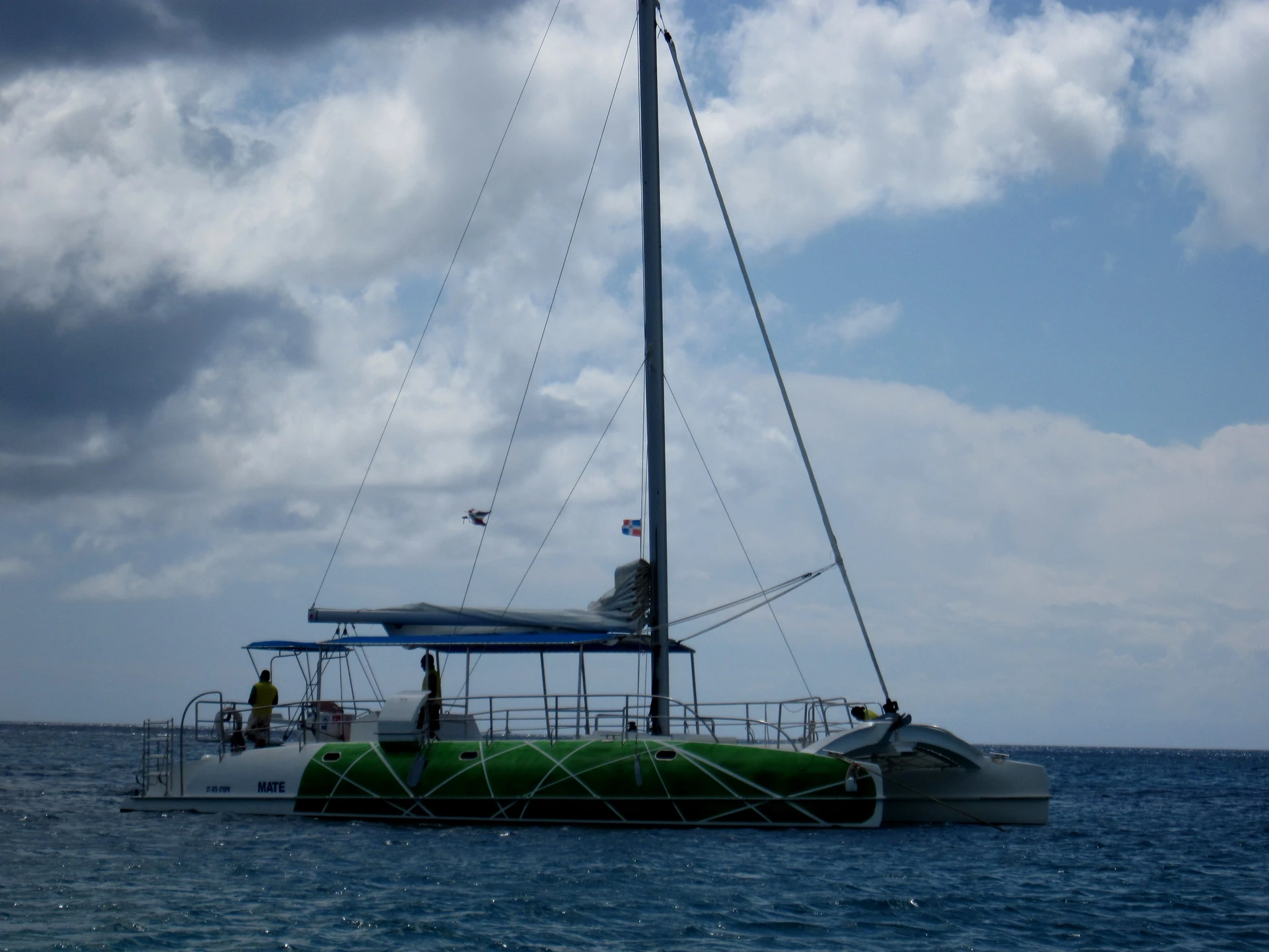Un catamarano a vela verde e bianco galleggia sull’acqua blu al ritorno dall’isola di Saona.