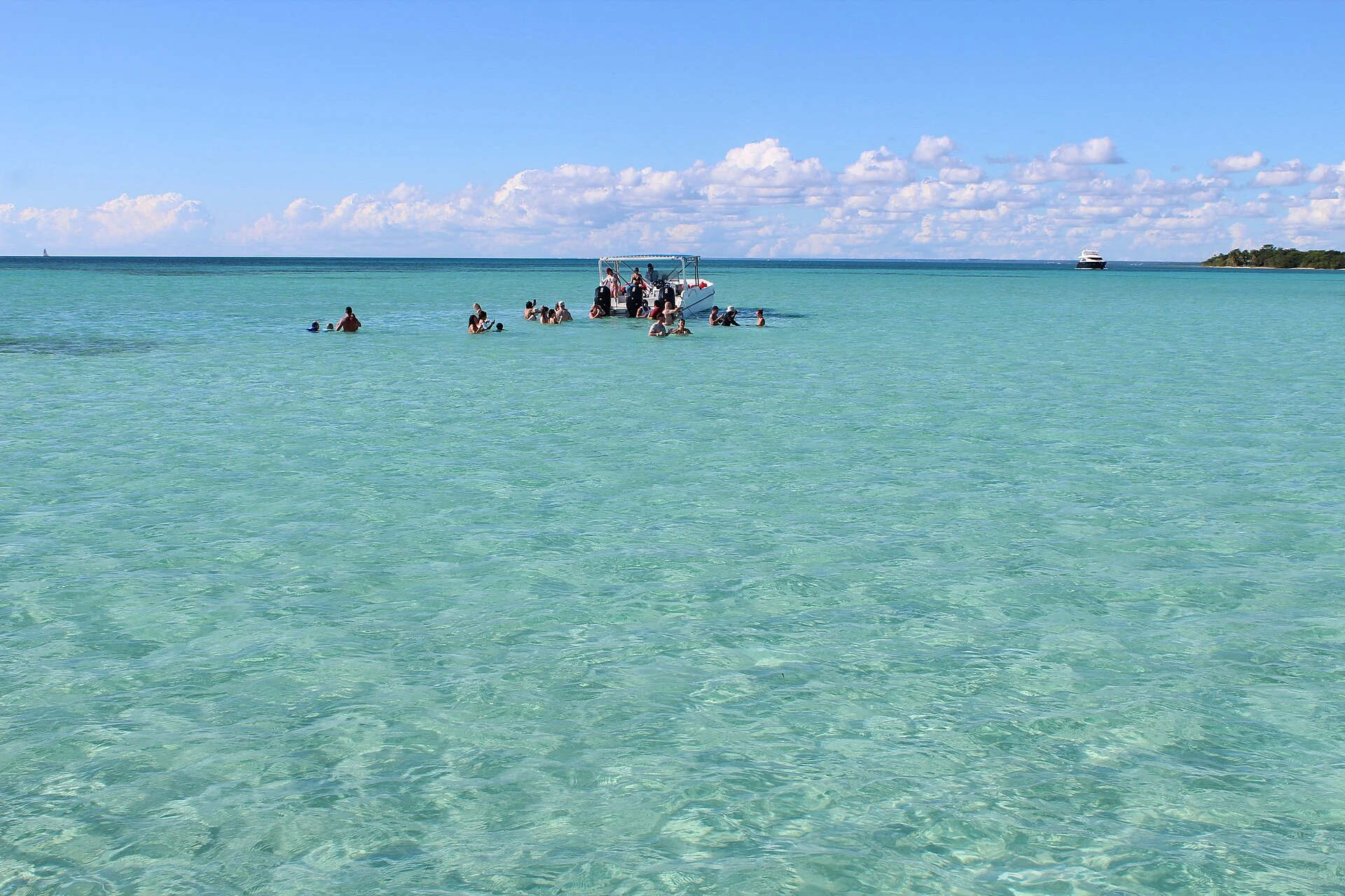 Visitors standing in the turquoise shallows of Piscina Natural near Saona