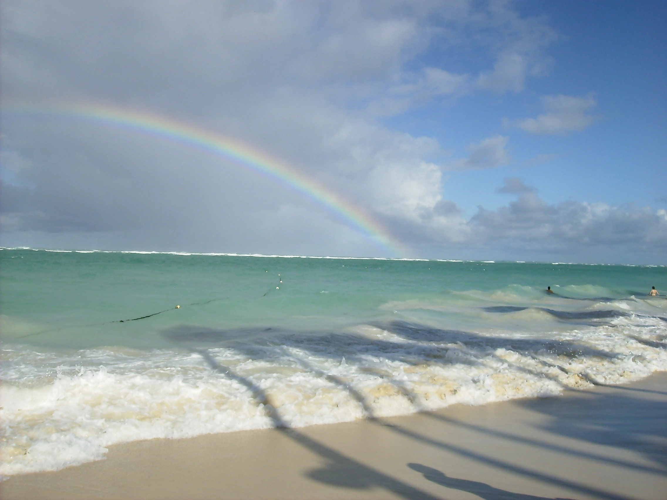 Un arcobaleno sovrasta il mare turchese e la costa bianca di Saona.