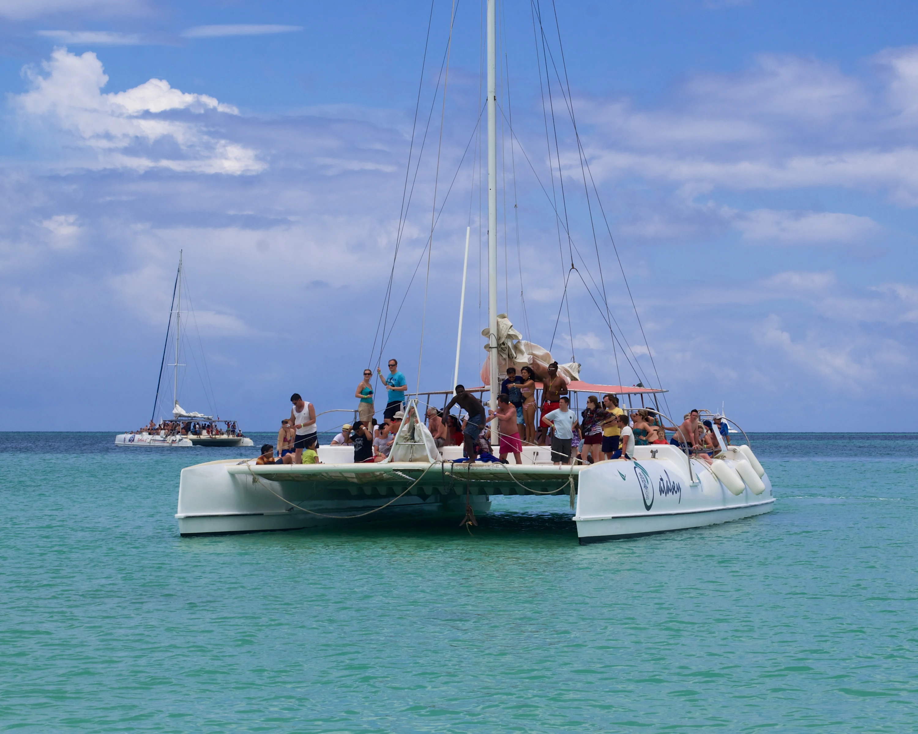 Un catamarano a vela con visitatori a bordo galleggia in acque turchesi vicino a Saona.