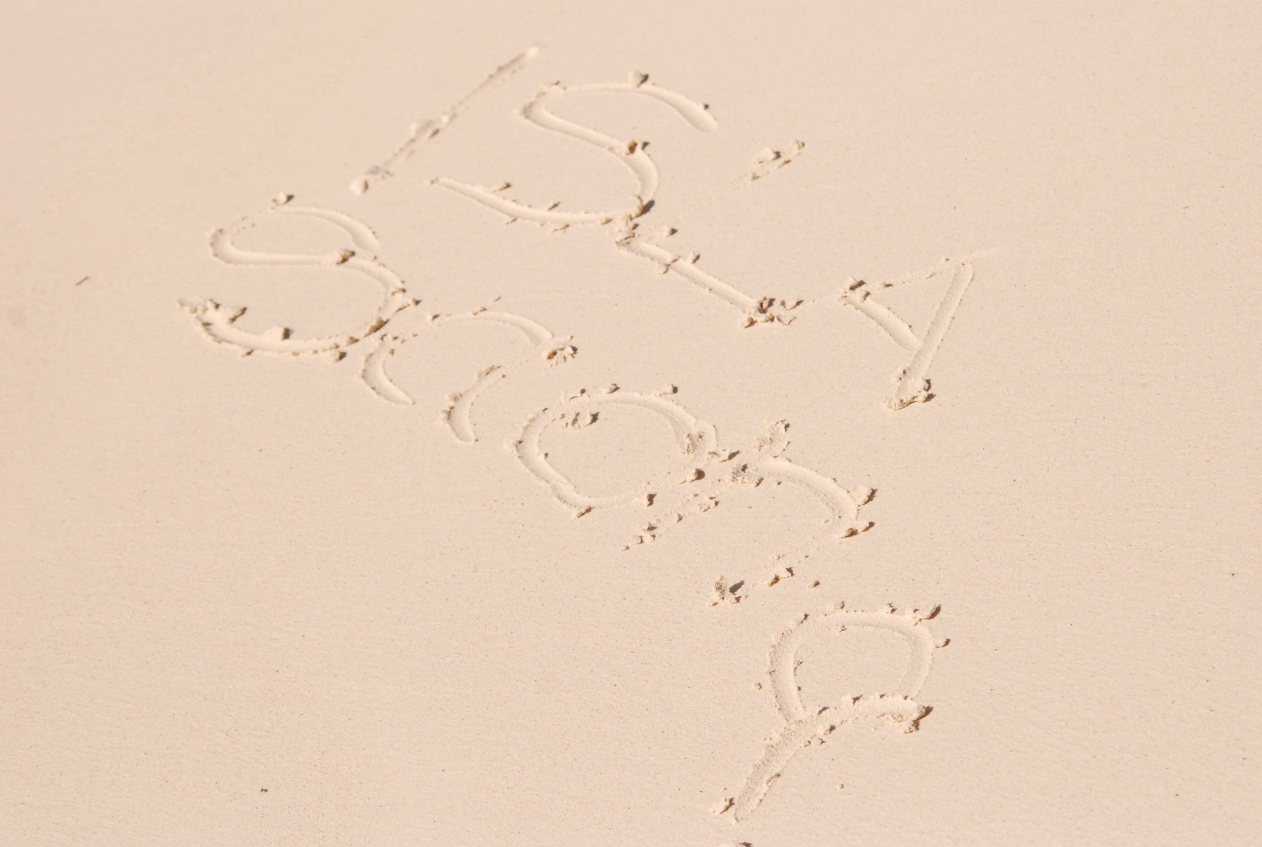 Der Name Isla Saona ist neben Fußspuren in hellen Strandsand gezeichnet.