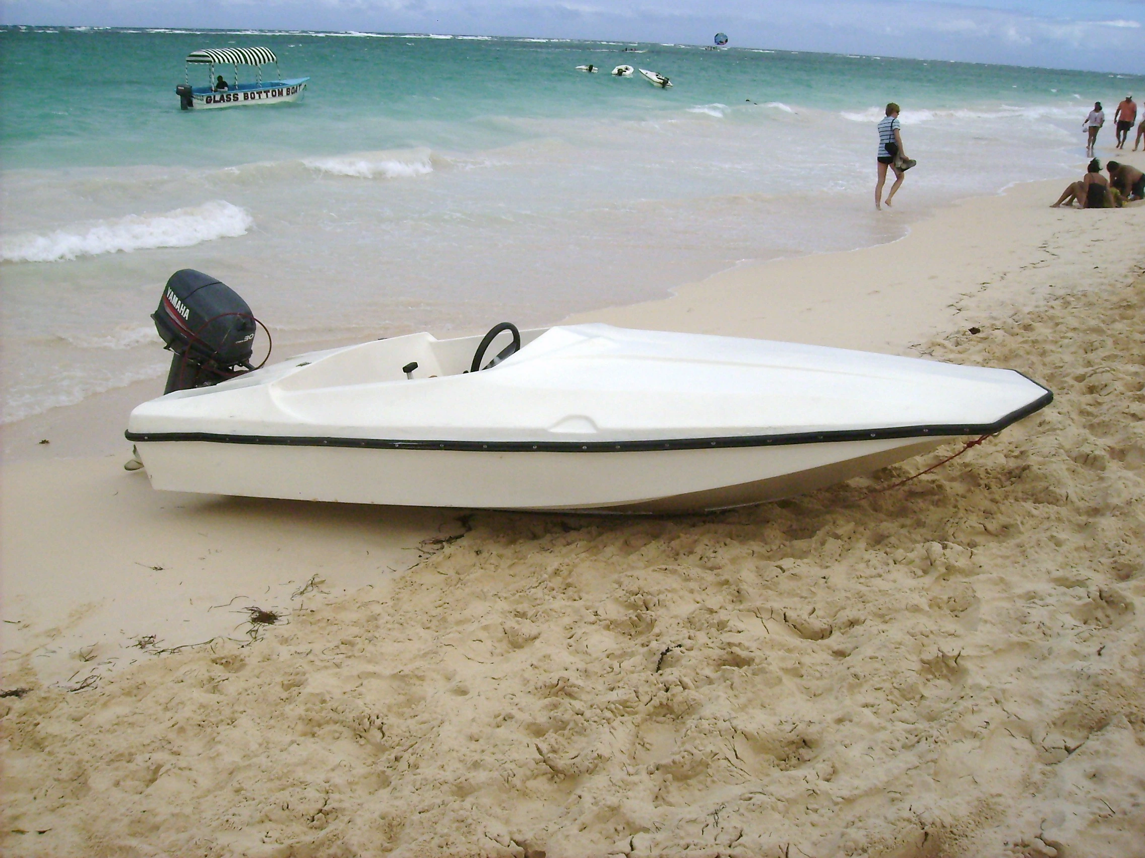 Una lancha blanca descansa en la arena clara de Saona junto al mar turquesa.
