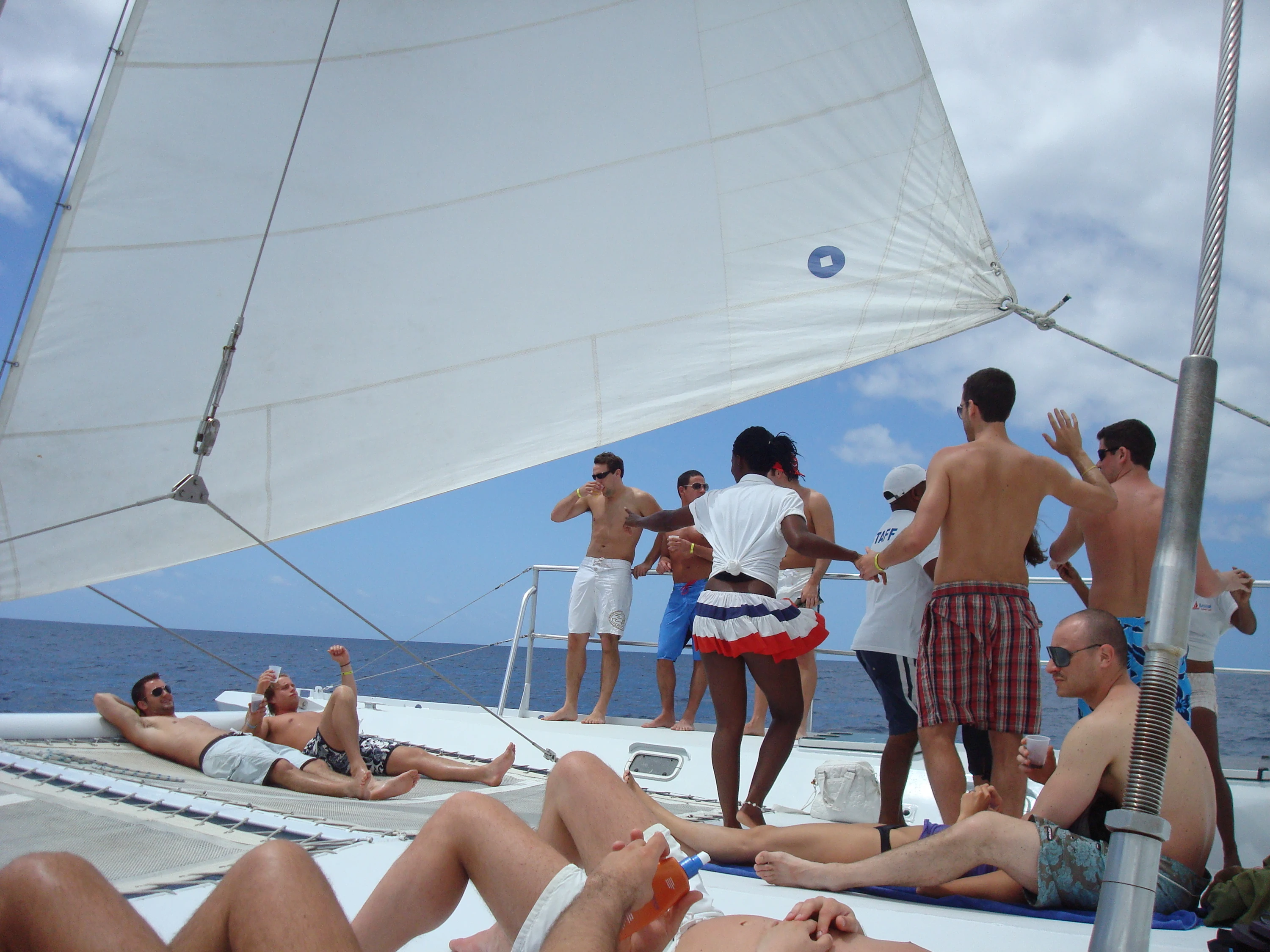 La vela di un catamarano si innalza sopra i passeggeri e l’acqua blu dei Caraibi durante un viaggio verso Saona.