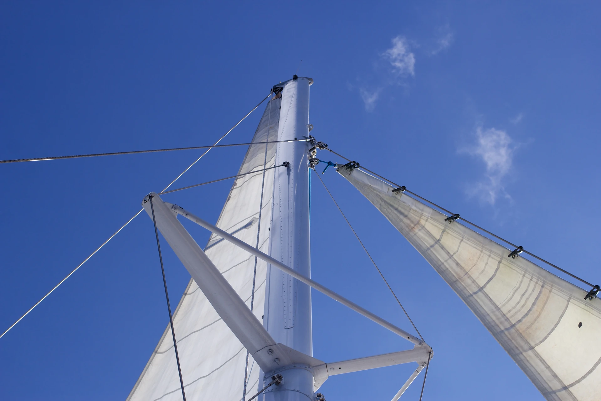 Le vele bianche e il sartiame di un catamarano si stagliano sul cielo azzurro durante un’escursione a Saona.