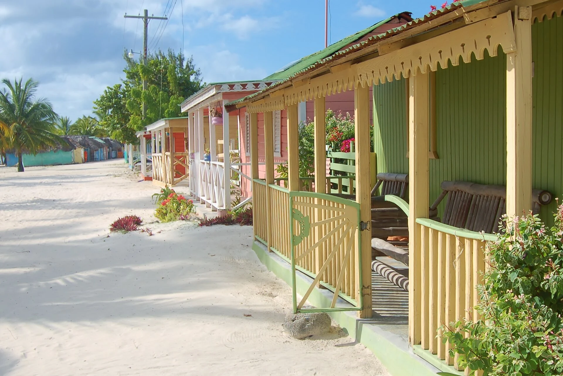 Colorful wooden beachfront houses along a sandy lane on Saona Island