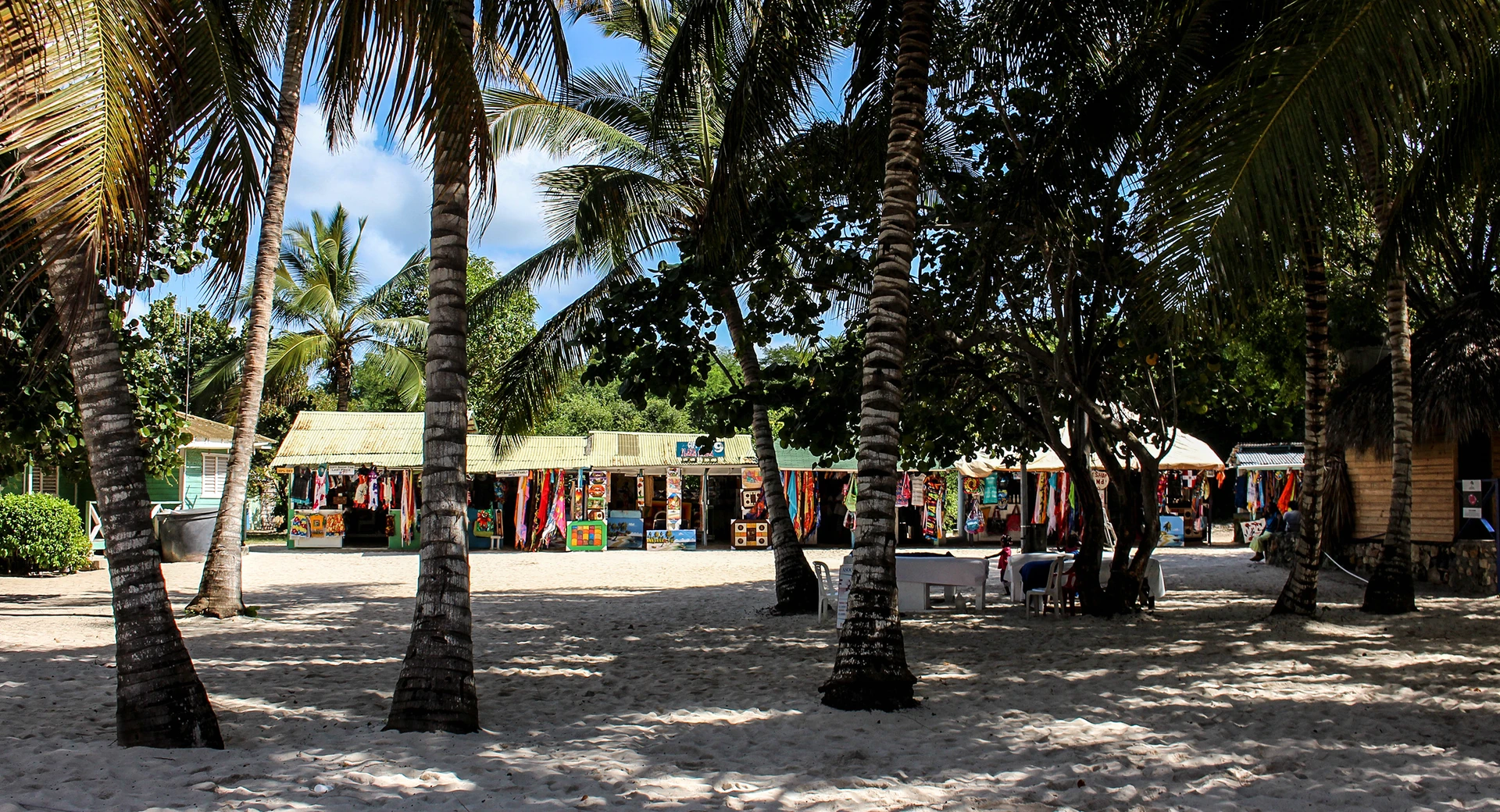 Bancarelle di souvenir si trovano sotto le palme da cocco in una radura sabbiosa di Saona.